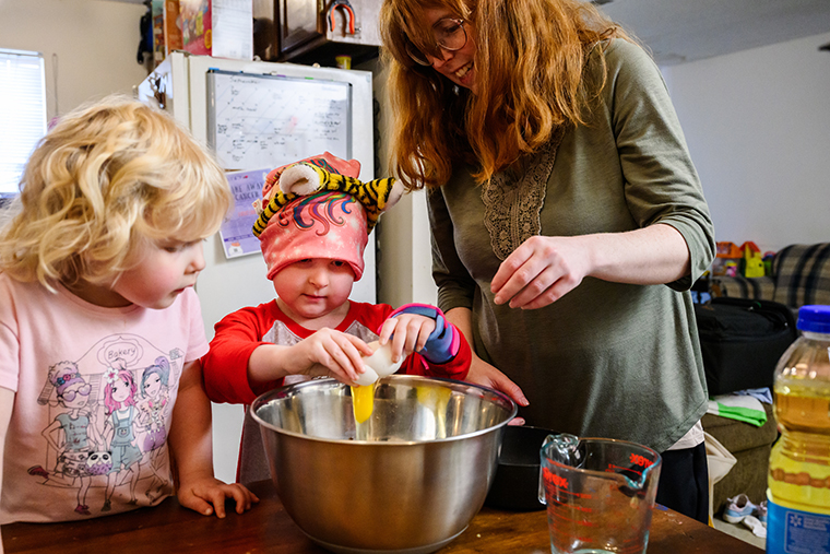 Sophie Bergen cracks an egg into a bowl of cake batter as her mom, Beth, and sister, Madison, watch at their home in Springfield, Missouri.