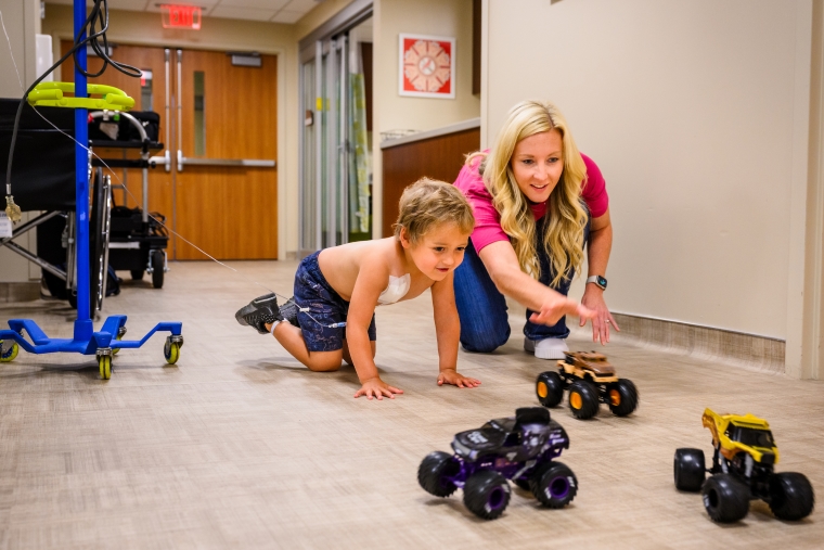 Bennett and Tara play with toy trucks in clinic while Bennett receives maintenance treatment for acute T-cell lymphoblastic leukemia.