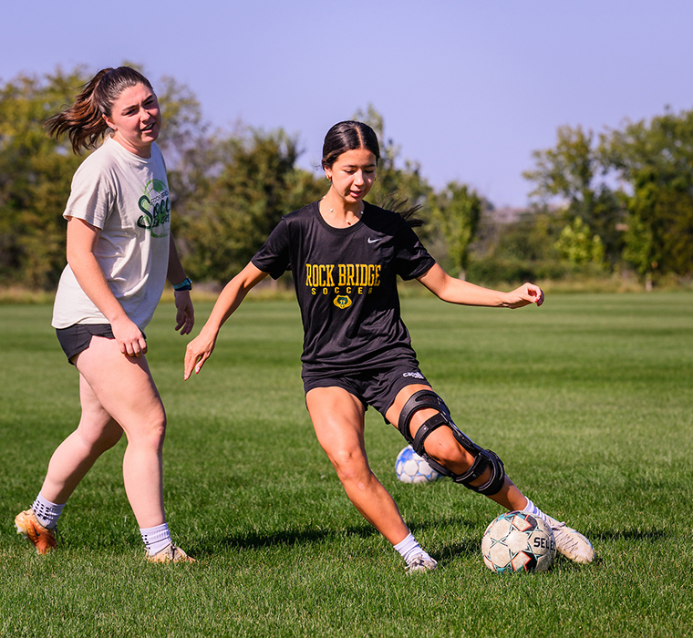 Lia dribbles the ball during a drill, wearing a protective brace on her knee after undergoing successful ACL and menisci reconstruction surgery.</em>