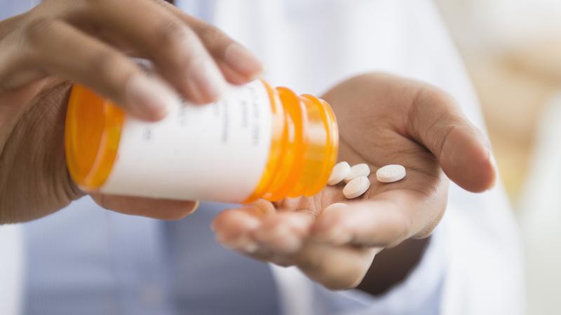 person pouring pills from pill bottle