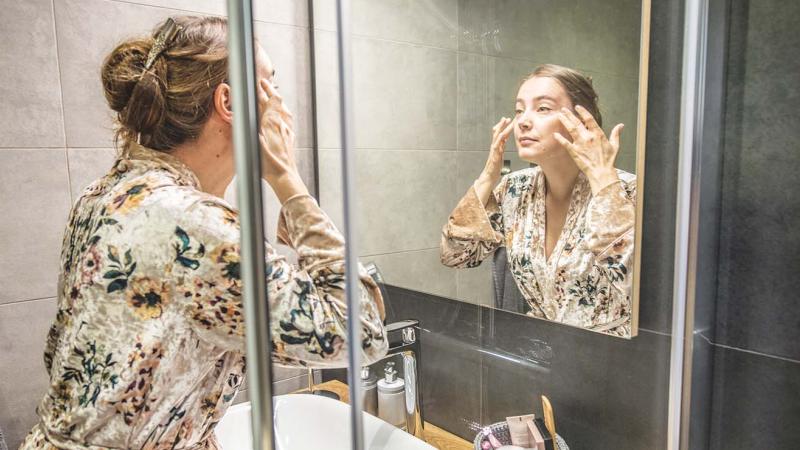 Woman looking at her face in the mirror