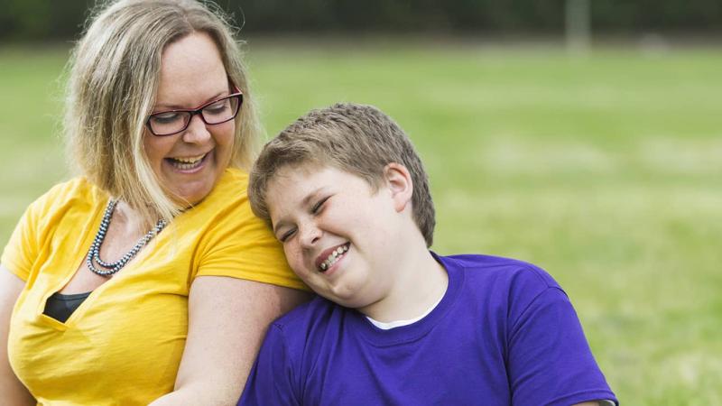 Mother and son sitting outside laughing