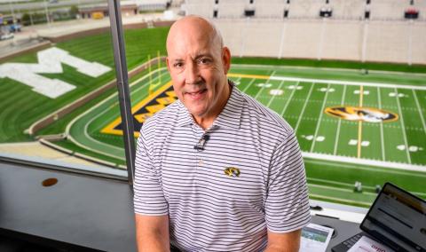 Man standing in a sports stadium box suite.