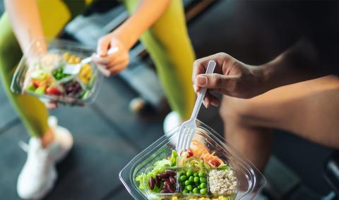 Two athletes sitting down eating a meal.