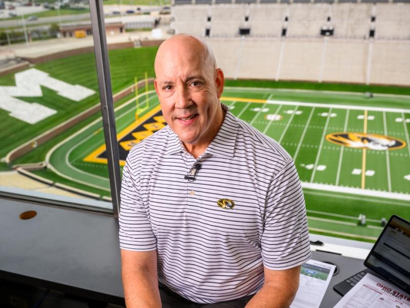 Man standing in a sports stadium box suite.