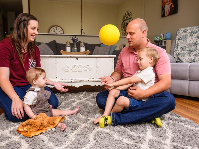 A photo of a family sitting on the floor of their living room.