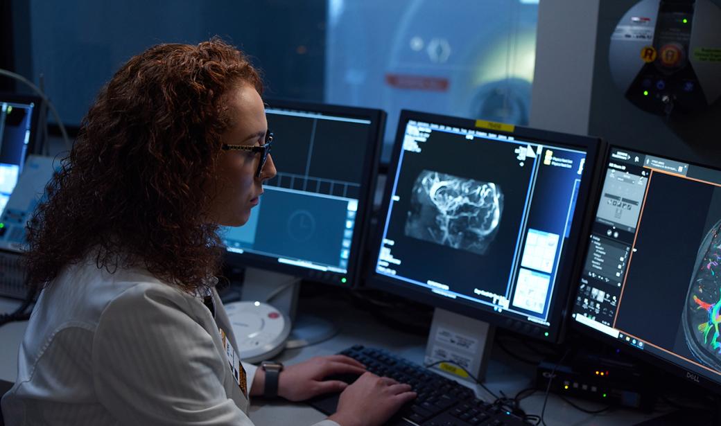 A medical professional looking at a scan on a computer.