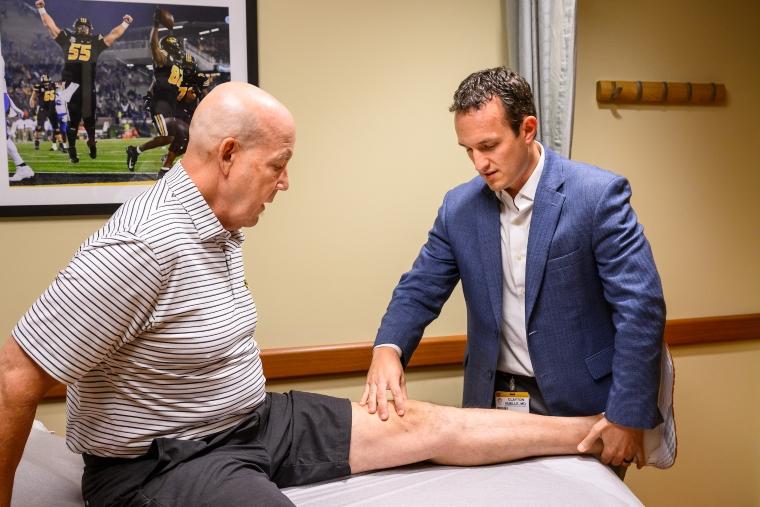 Doctor is inspecting the knee of a patient.